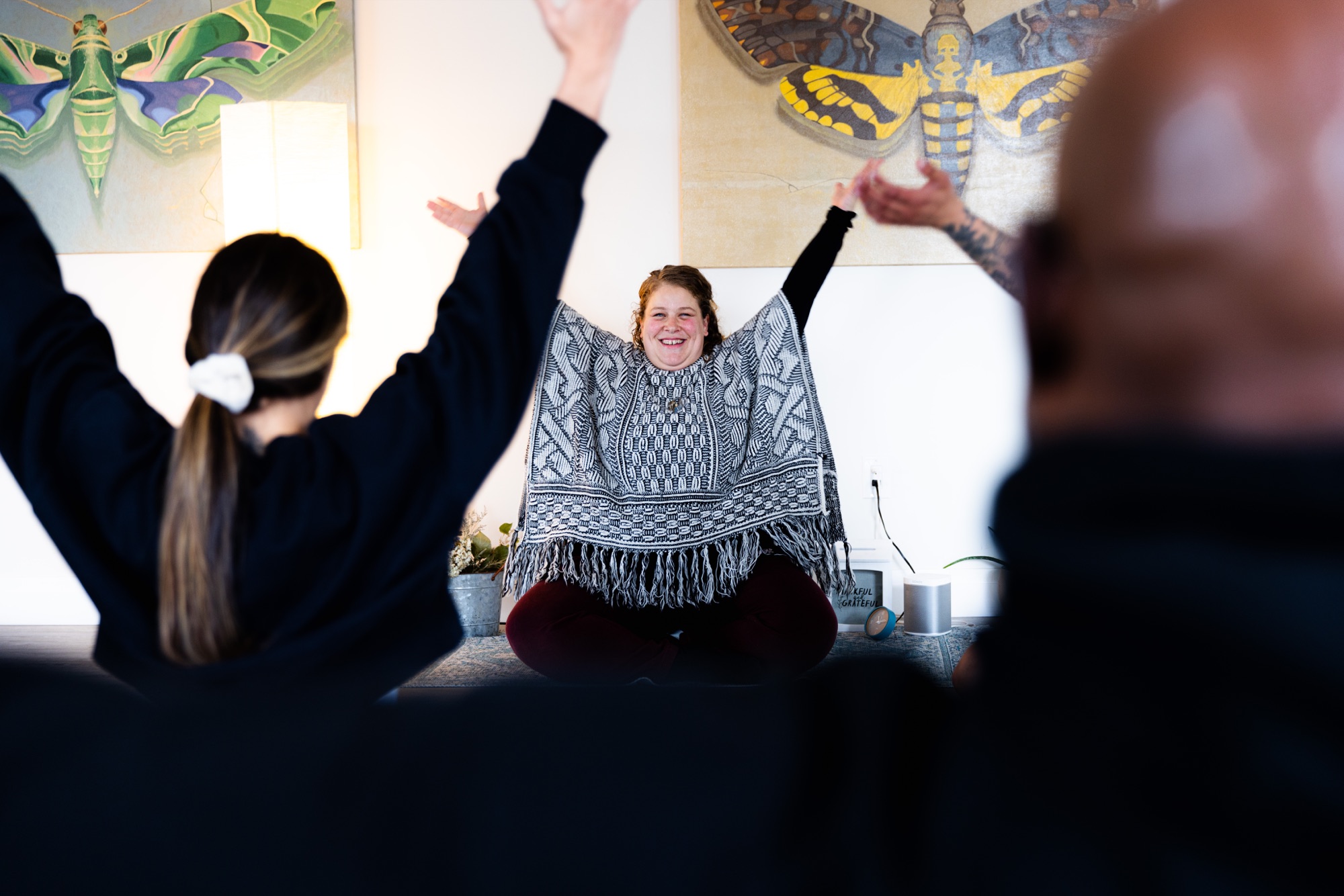A somatic class raising their arms together, led by their instructor
