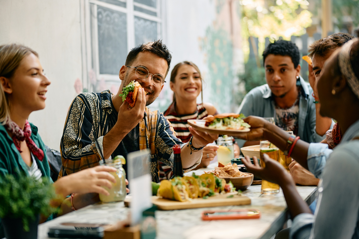 A group of friends having dinner on a patio, eating tacos and socializing